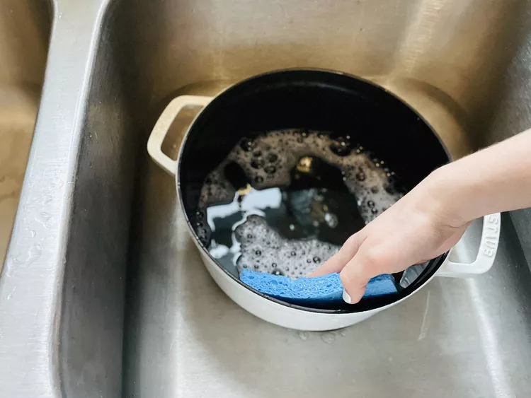 How to clean a Dutch oven - Scrubbing Dutch oven with a sponge and soapy water